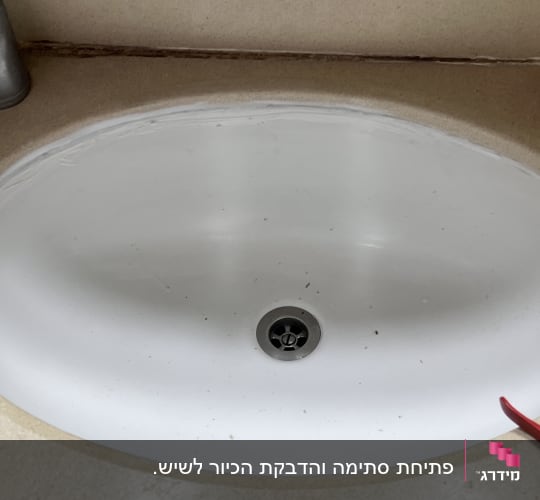 כיור לבן עם ברז וכמה לכלוכים